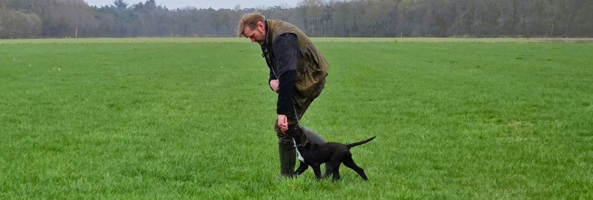 Jager leert zijn puppy het volgen.